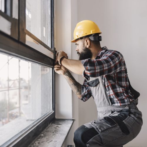 A repairman fixing windows in new apartment.